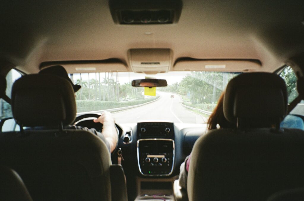 View from the back seat of a family car, looking past the front seats to an open road ahead