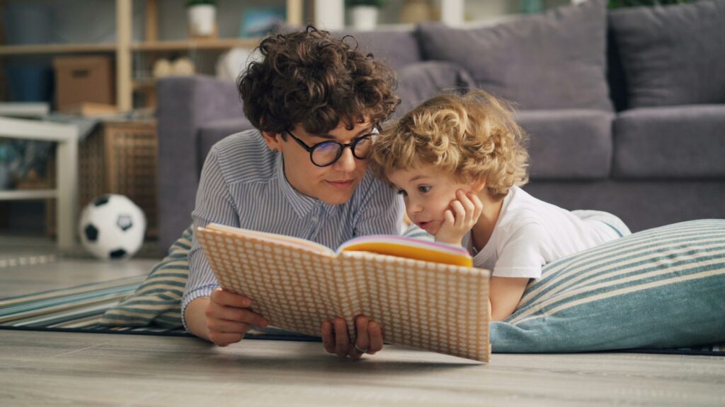 A woman and a child lying on the floor reading a picture book together
