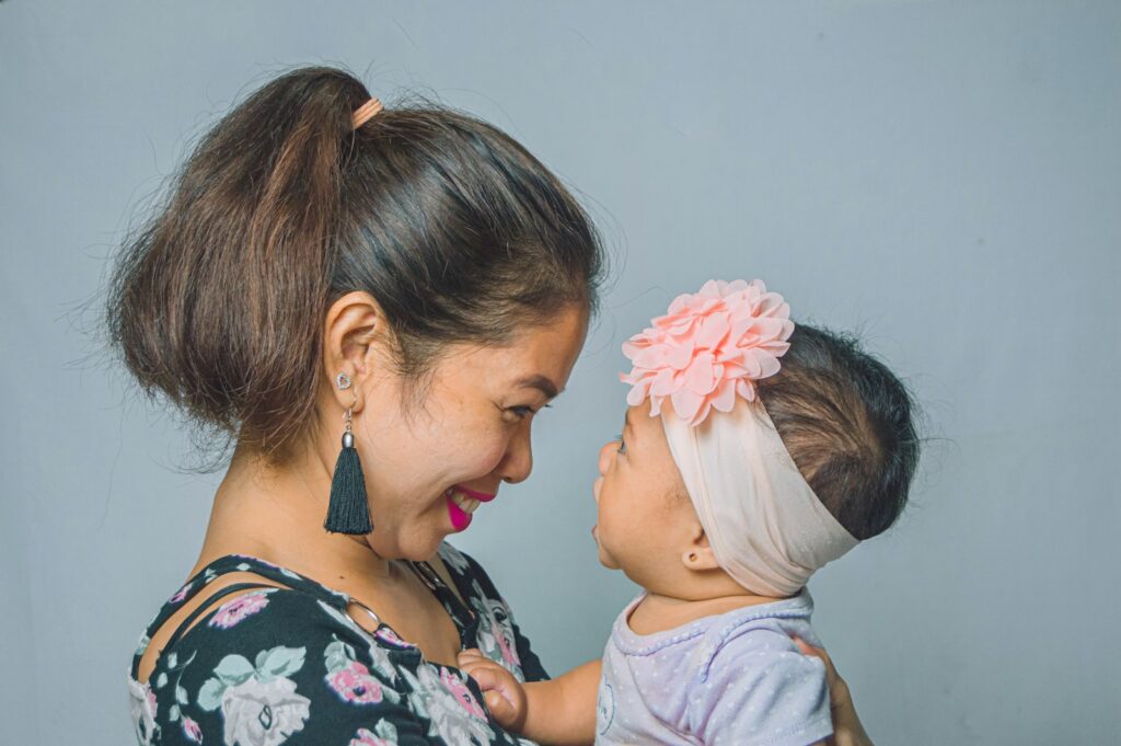 A mother and her baby smile at each other face to face